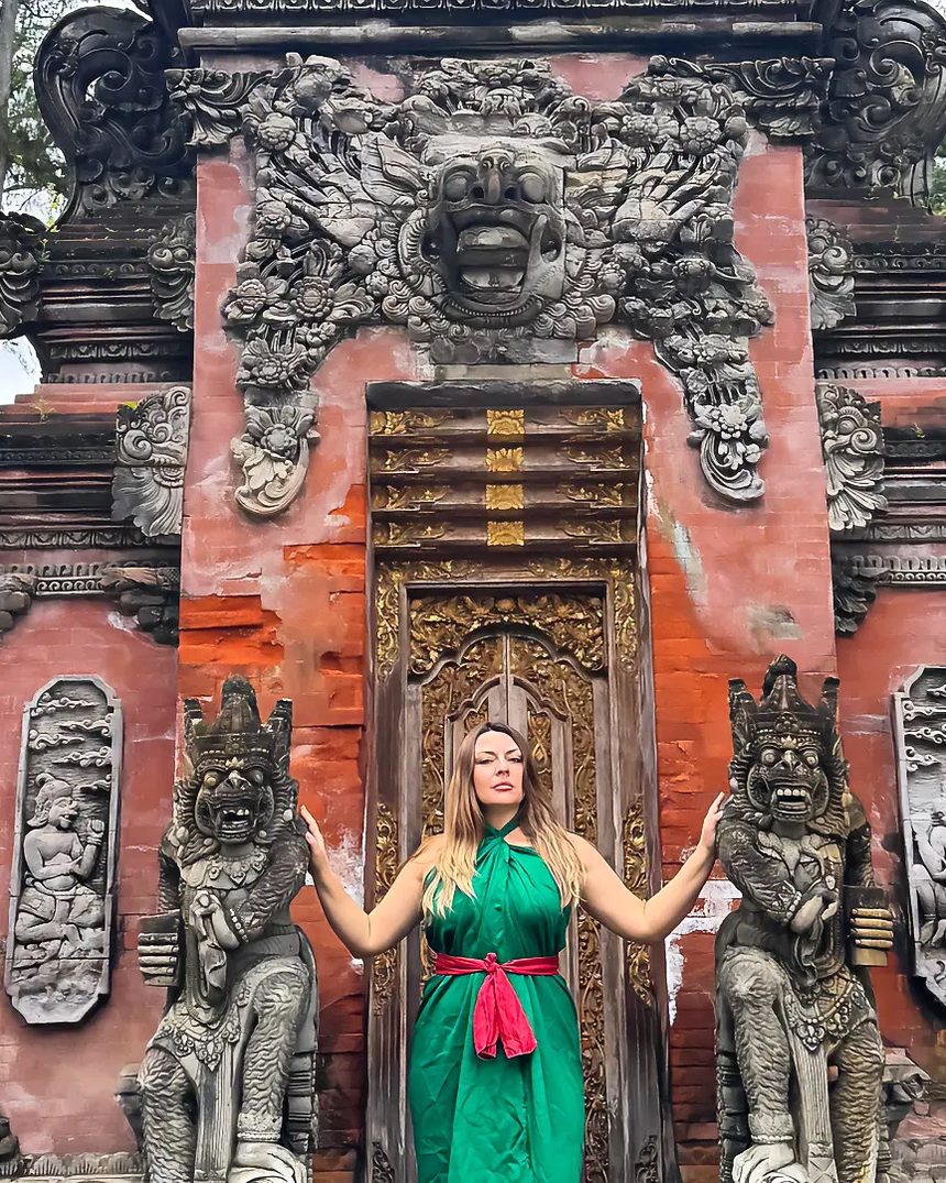 Delfina standing between temple guardians, arms open