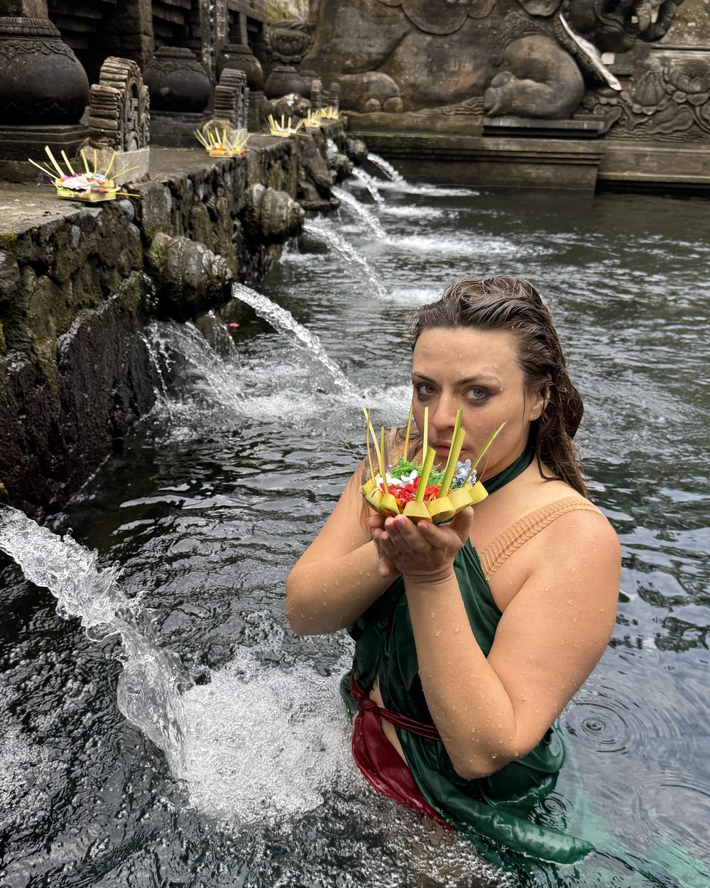 Delfina in the waters of a Balinese temple, holding an offering