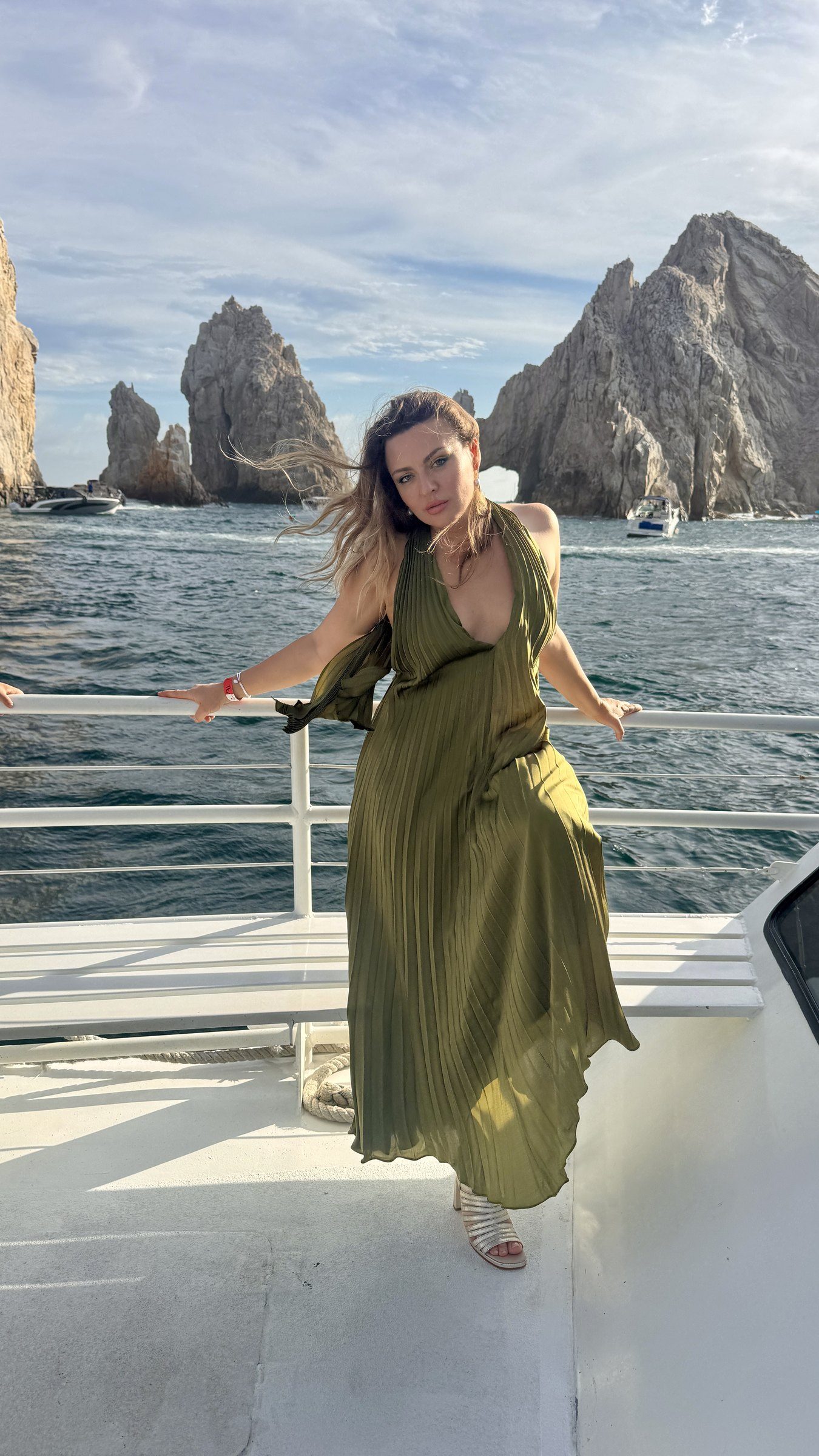 Delfina Alden in an olive dress at the sea arch of Cabo San Lucas