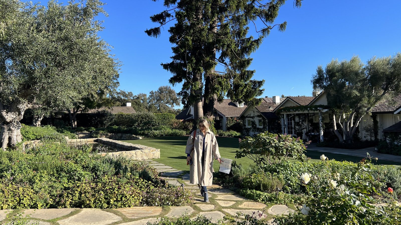 Delfina walking a garden path between roses